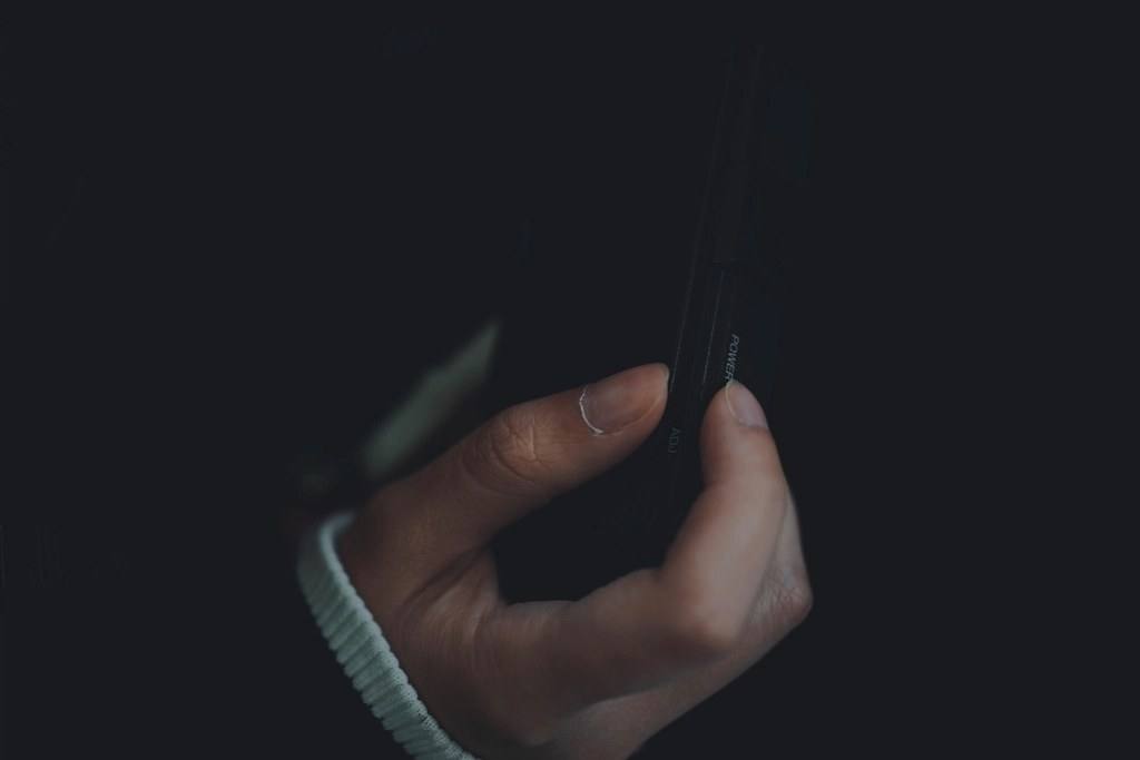 Una mano sosteniendo un celular en la oscuridad